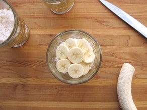 Layering sliced bananas in a parfait cup.