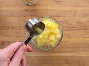 Adding pineapple chunks to a parfait cup.