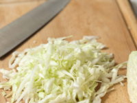Freshly chopped cabbage on a wooden cutting board with a sharp knife