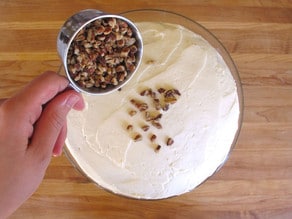 Topping a round cake with nuts.