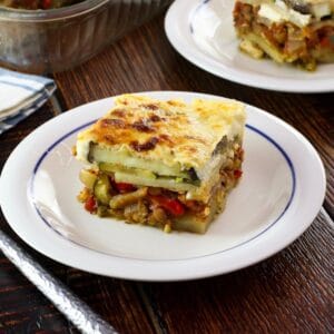 Close up of slice of Roasted Vegetable Moussaka on a small plate on wood table.