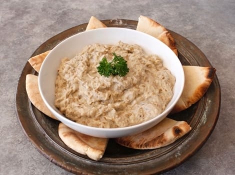 Creamy Baba Ghanoush in a bowl surrounded by pita chips.
