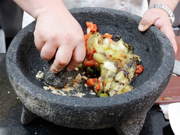 Mashing tomatoes and peppers.