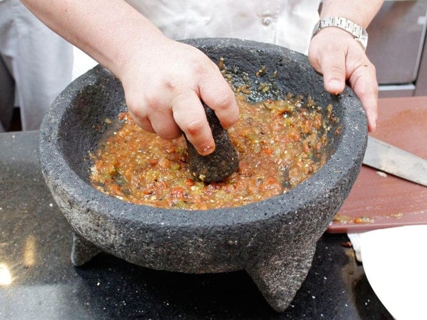 Mashing tomatoes and peppers.