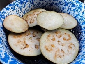 Sliced eggplant rounds in a bowl.