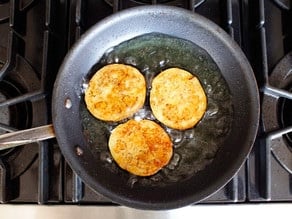 Frying eggplant rounds in a skillet.