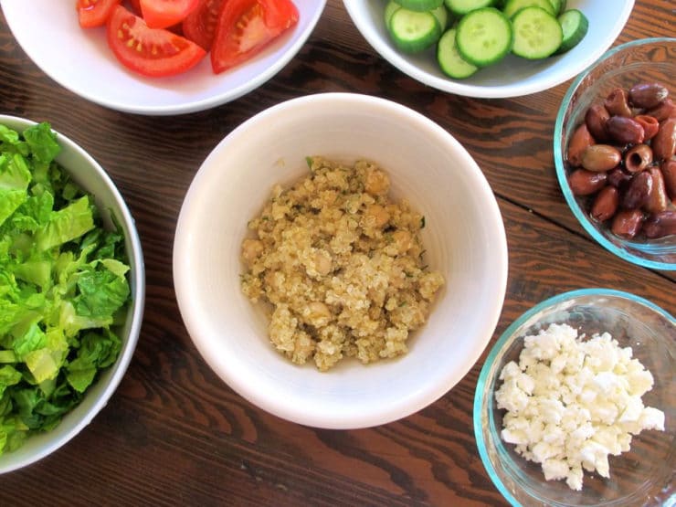Quinoa in a bowl surrounded by bowls of salad toppings.