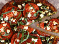 A tomato pesto tart topped with fresh basil leaves on a tart