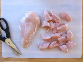 Cutting chicken breasts into bite-sized pieces.