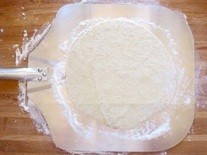Pizza dough on a parchment sheet.