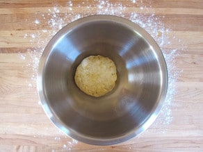 Pizza dough ball in a greased mixing bowl.