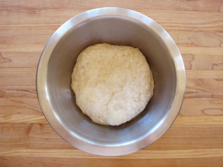 Proofed pizza dough in a mixing bowl.