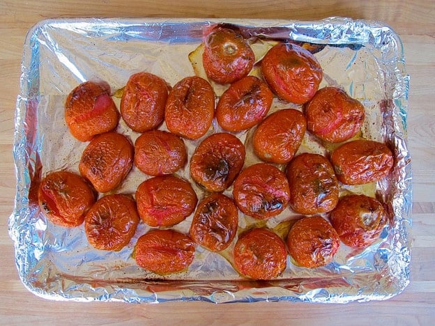 Roasted tomatoes on a lined baking sheet.