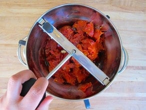 Running crushed, roasted tomatoes through a food mill.