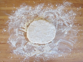 Biscuit dough in a disc on a cutting board.