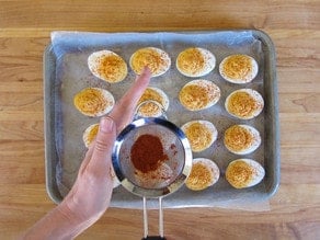 Dusting deviled eggs with paprika.