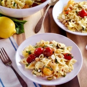 Plate of Lemon Pasta Salad made with ribbon pasta, tomatoes, and lemon served on table with fork and table napkins