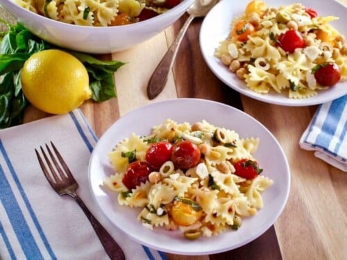 Plate of Lemon Pasta Salad made with ribbon pasta, tomatoes, and lemon served on table with fork and table napkins