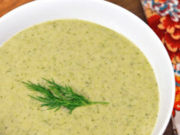 Creamy broccoli tahini soup in a white bowl garnished with fresh herbs