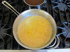 Adding broth to rice in a pan.