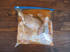 Chicken pieces marinating in a bag.