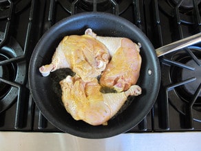 Browning chicken pieces in a skillet.