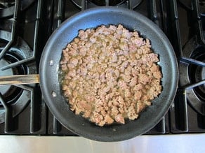 Ground lamb browning in a skillet.