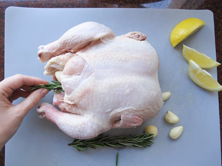 Adding aromatics to chicken cavity.