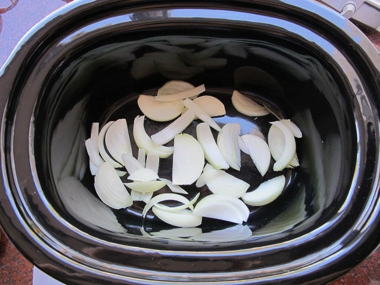 Onions layered in a slow cooker.