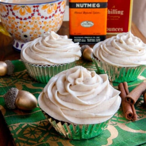 Three pumpkin cranberry cupcakes with frosting and a touch of cinnamon