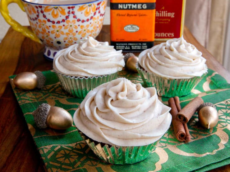 Three pumpkin cranberry cupcakes with frosting and a touch of cinnamon