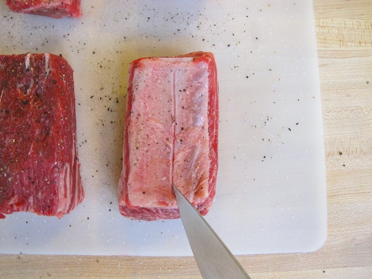Scoring beef short ribs with a knife.