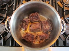 Beef short ribs browning in a pot.