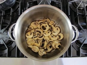 Sliced mushrooms browning in a pot.