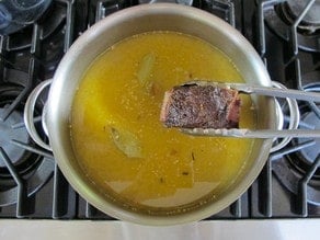 Removing short ribs from pot of soup.