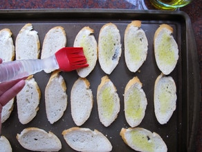 Brushing sliced baguette with olive oil.