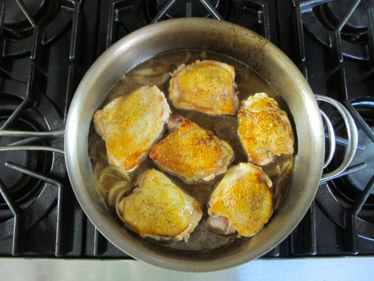 Chicken broth added to thighs in pan.