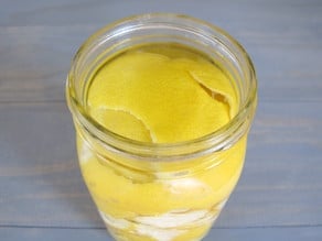 Lemon peels covered with clear liquid in open mason jar.