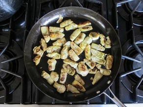 Artichoke hearts in a saute pan.