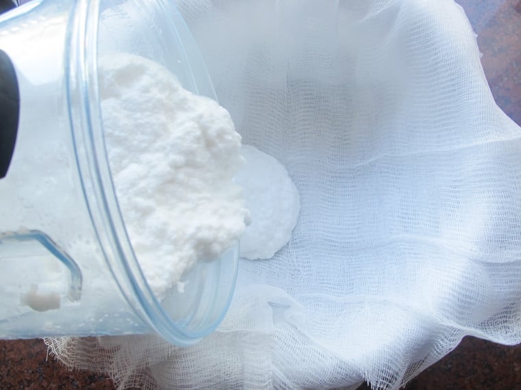 Pouring coconut milk into cheesecloth.