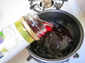 Grape juice being added to a saucepan.