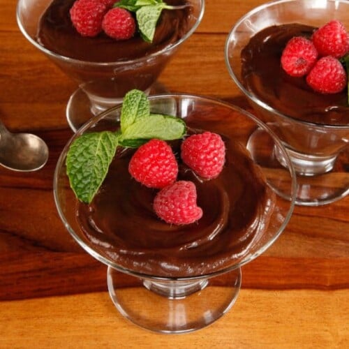 Horizontal image of vegan dark chocolate mousse served with raspberries and mint.