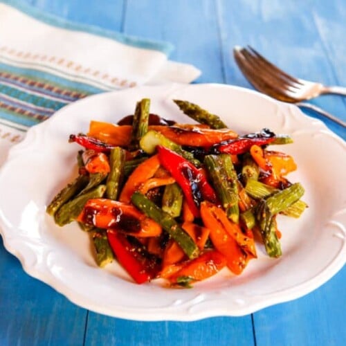 Roasted sweet mini peppers and asparagus on a plate with a fork