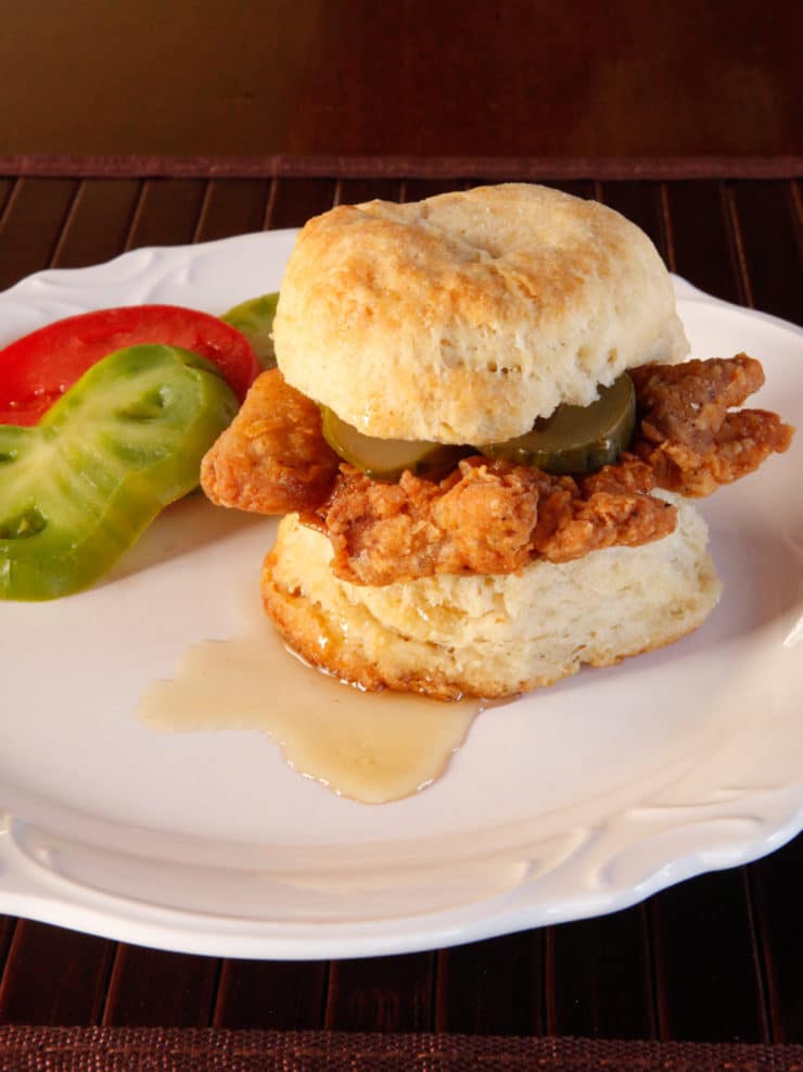 Fried Chicken Sliders - Crispy, flavorful fried chicken thighs on freshly baked biscuits with pickle slices and a drizzle of honey. 