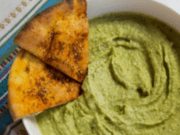 Green Spicy Jalapeño hummus with pita chips served on a white bowl