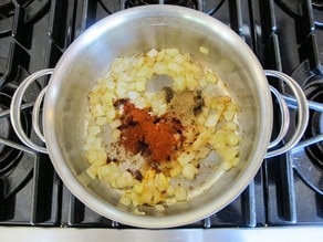 Spices added to onions in a pan.