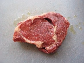 Ribeye steak seasoned with salt and pepper.