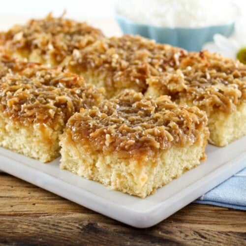 A plate full of square daisy flower cake slices, accompanied by a daisy flower in the background