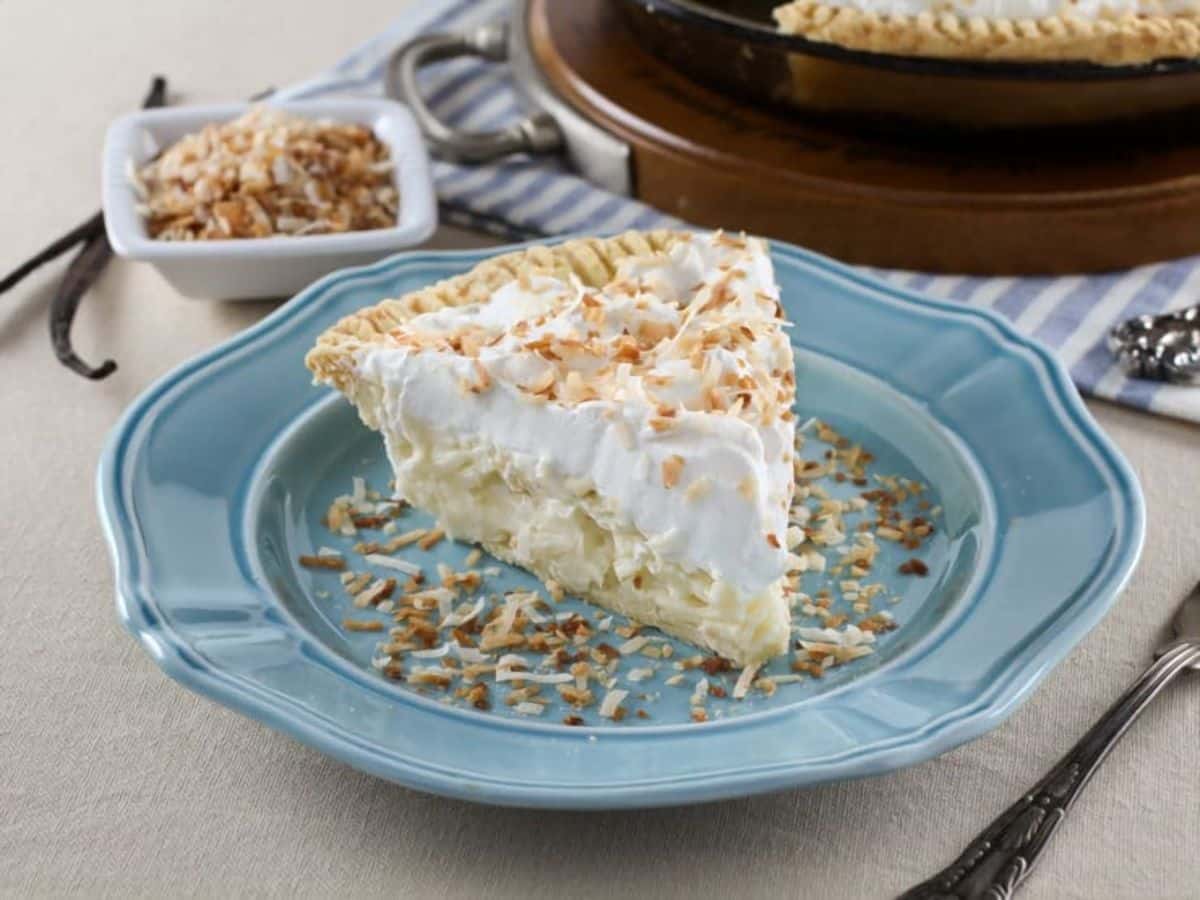 A slice of Coconut Cream Pie on a blue plate, showcasing its creamy filling and golden crust