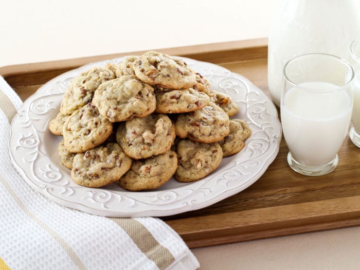 A tray with Date Cookies and a glass of milk on a wooden table